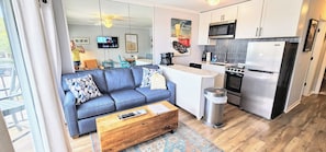 Relax in a spacious living area with a sofa and coffee table, kitchen with stainless steel appliances, and a large mirror.