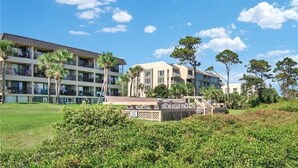 Un hôtel à plusieurs étages doté de balcons, d’une piscine et d’une végétation luxuriante.