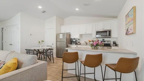 A modern kitchen with white cabinets, a central island, and bar stools. - Stunning NEW / 2BR/Walk to Beach/Sleeps 5/Bunk (Panama City)