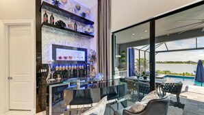 Eine moderne Bar mit einer Glastheke, Regalen voller Flaschen und einem Fernseher.