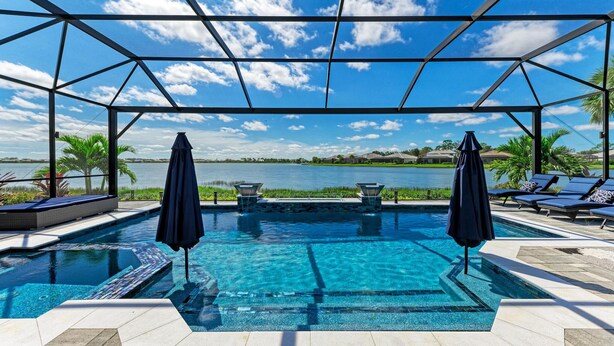 Ein Pool mit Seeblick, umgeben von Liegestühlen und Sonnenschirmen.