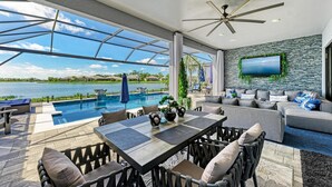 Ein moderner Außenbereich mit Pool, Sitzgelegenheiten und einem an der Wand montierten Fernseher.
