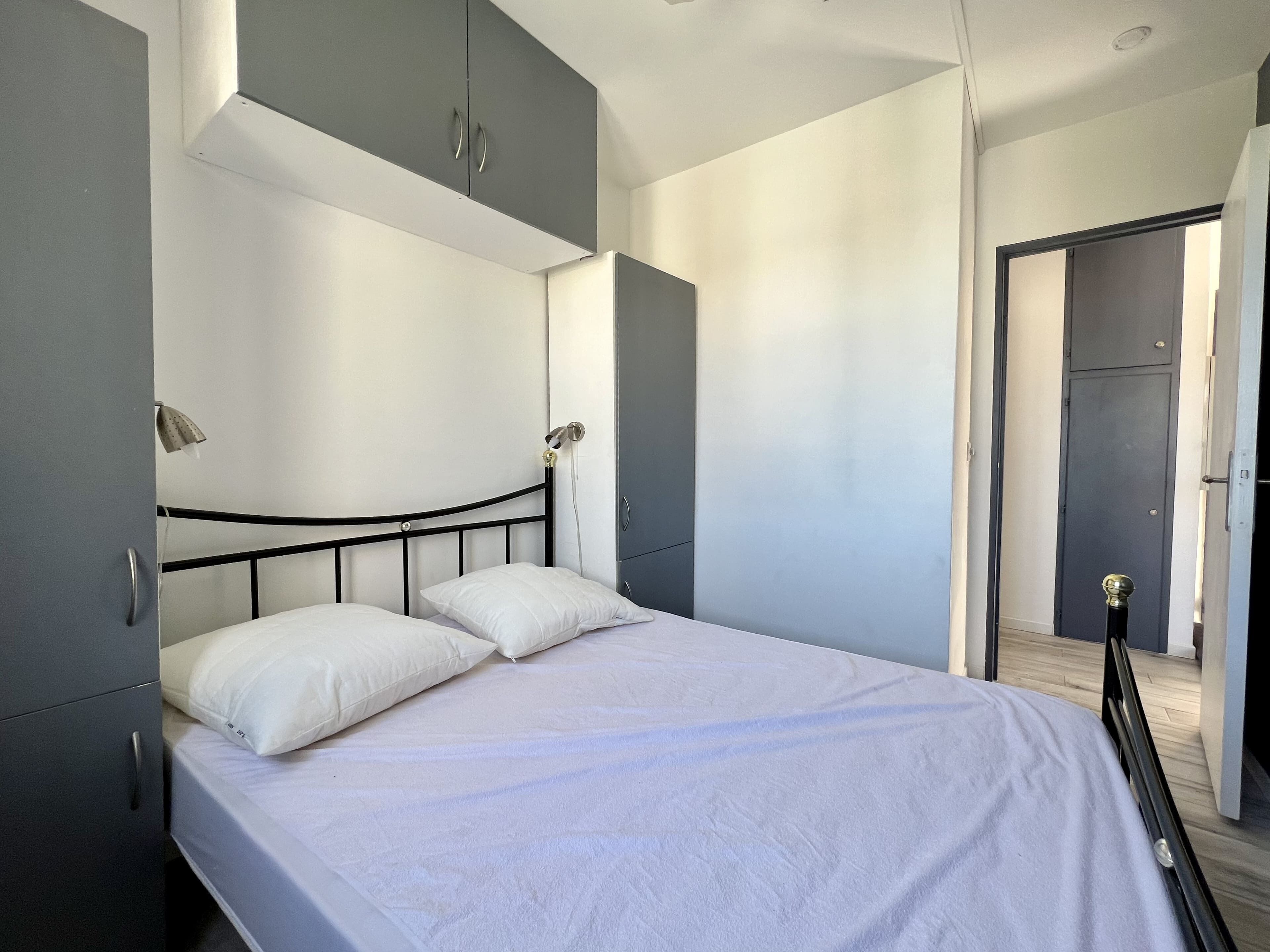 Een slaapkamer met een bed, twee bedlampen, een kledingkast en een deur naar een andere kamer.