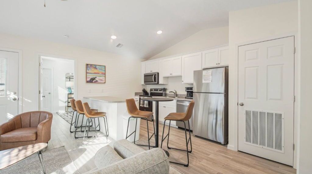 A modern kitchen with white cabinets, stainless steel appliances, and a central island with bar stools.
