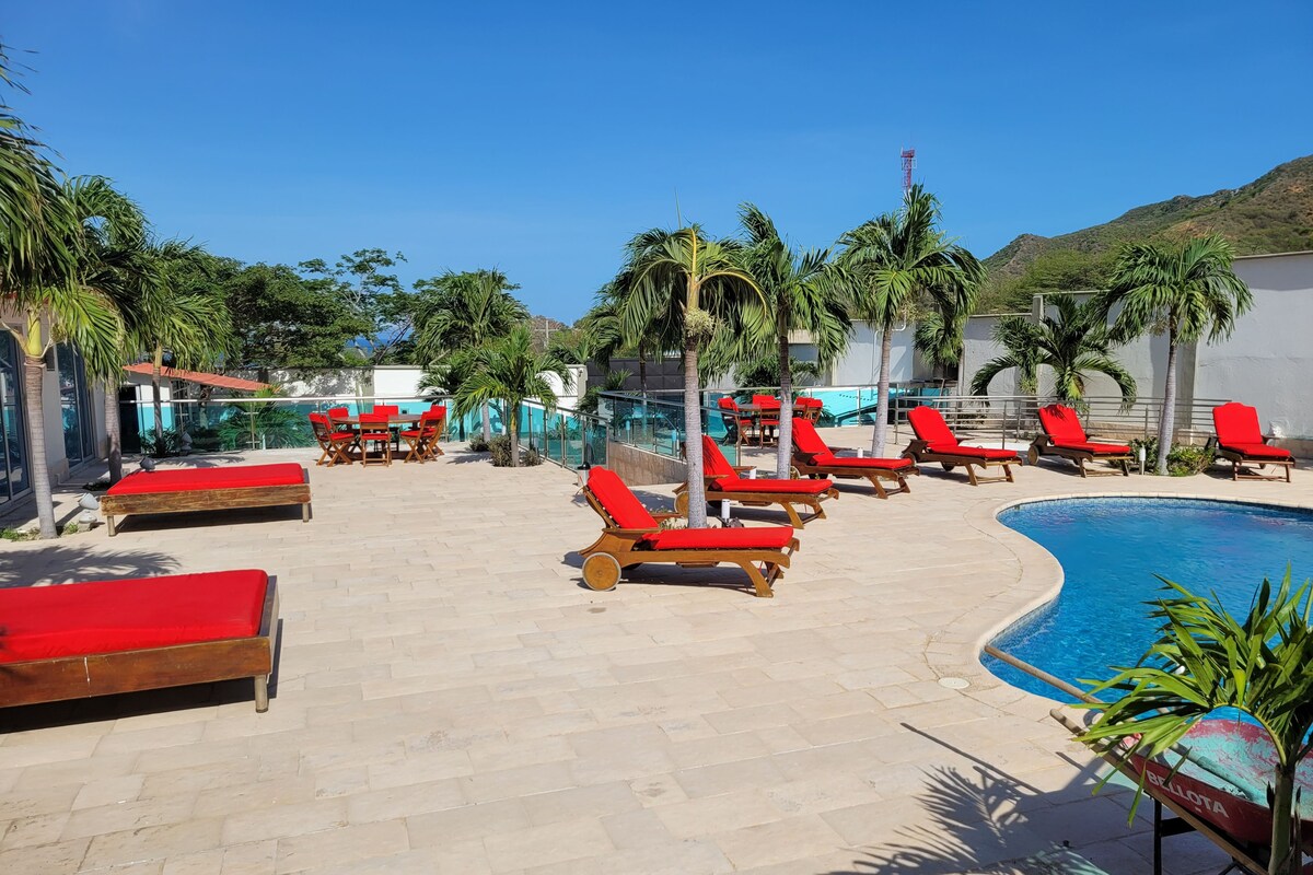 A poolside area with red lounge chairs and a swimming pool.