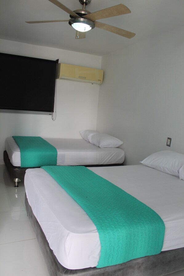 A hotel room with two beds, a ceiling fan, and a window with a black blind.