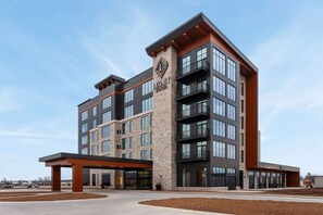 Un hotel de varios pisos con un llamativo letrero que dice 'Legacy Hotel', grandes ventanales y un diseño arquitectónico moderno.
