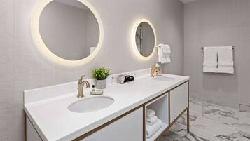 A modern bathroom with two sinks, a large mirror, and a marble floor.