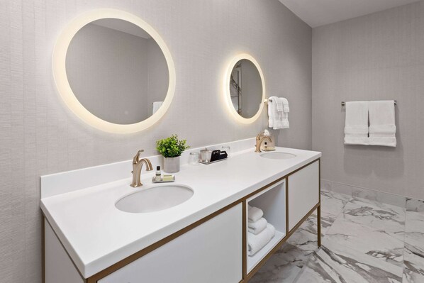 Une salle de bain moderne avec deux lavabos, un grand miroir et un sol en marbre.