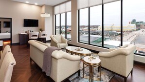 A modern hotel room with a large window, a sofa, two armchairs, a small table, and a TV. - Legacy Hotel Trademark Collection By Wyndham (Green Bay)