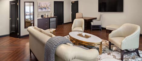 A spacious living room with a sofa, armchairs, a coffee table, and a dining area.