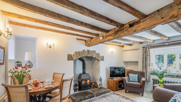 A cozy living room with exposed wooden beams, a stone fireplace, a television, and comfortable seating. - 2 bedroom accommodation in Eyam, near Bakewell (Eyam, near Bakewell)