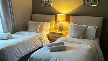 Una habitación de hotel con dos camas, una mesita de noche con lámpara y un adorno en la pared.