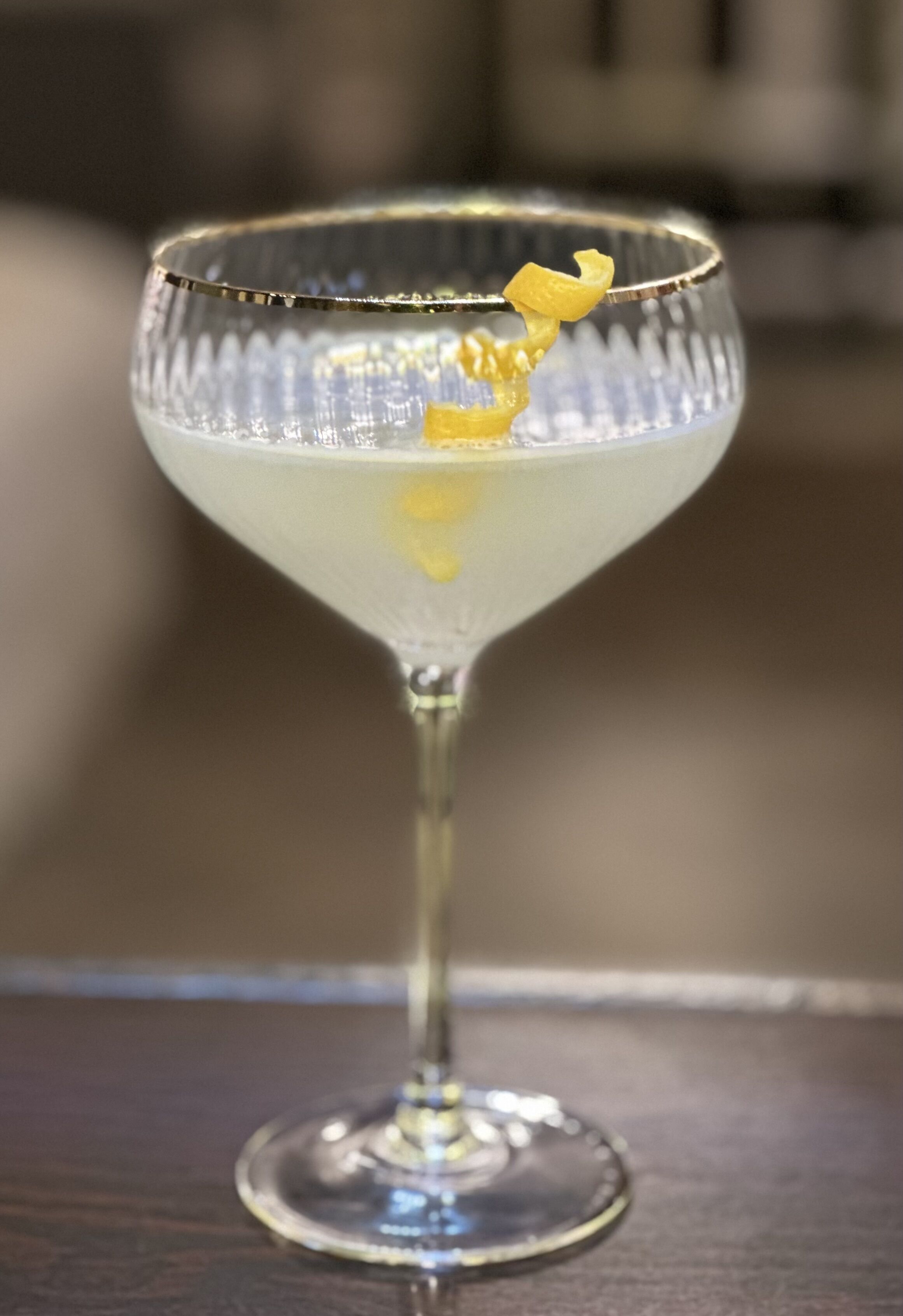Een cocktailglas met een citroen twist op een donker houten oppervlak.