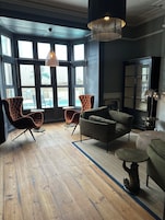 A spacious room with large windows, a fireplace, and modern furniture.