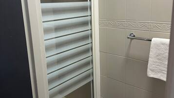 A bathroom with a glass shower door, tiled walls, and a towel rack.