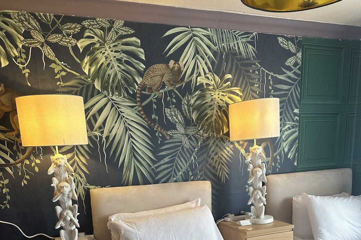 A hotel room with a bed, two bedside tables, lamps, and a wall mural.