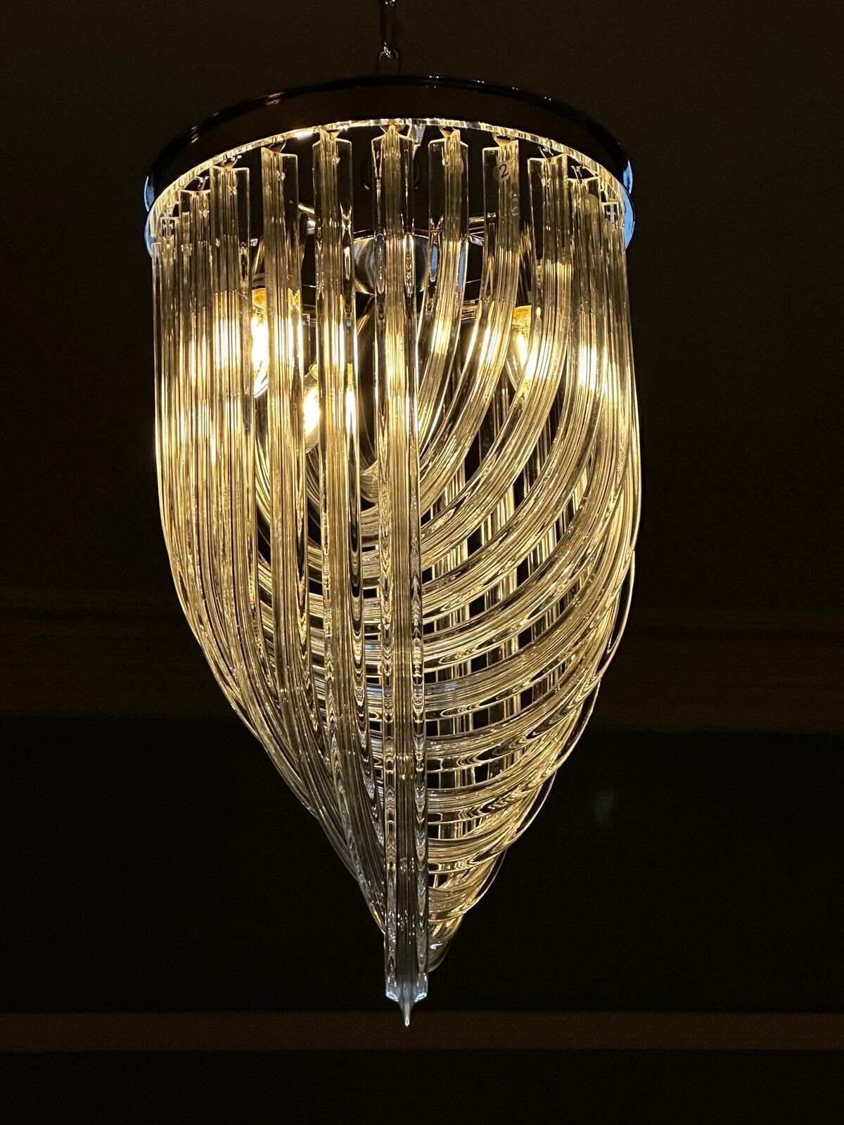 En kristallkrona med flera våningar av glas- och metallelement, hängande från taket.