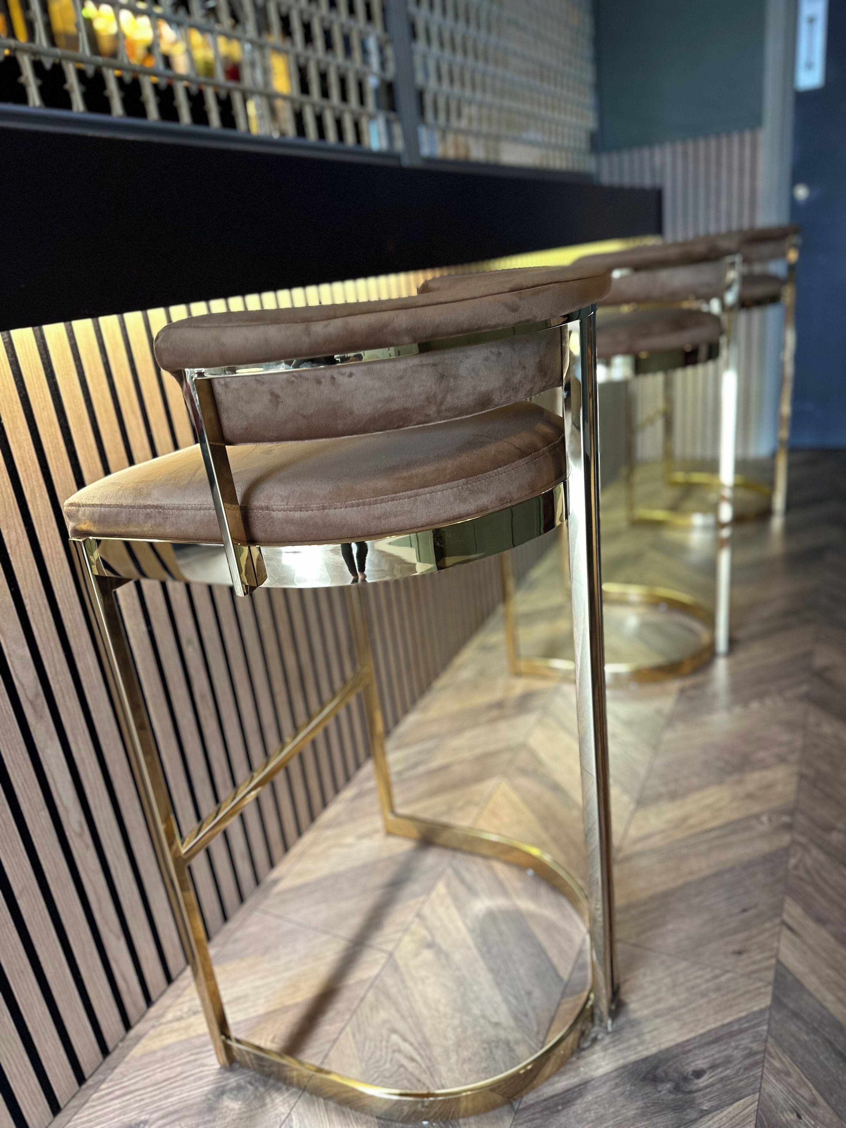 Ein Barbereich mit modernem Design, mit einer Bar und zwei Barhocker mit gepolsterten Sitzen und Metallgestellen.