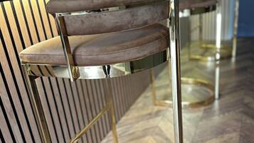 Ein Barbereich mit modernem Design, mit einer Bar und zwei Barhocker mit gepolsterten Sitzen und Metallgestellen.