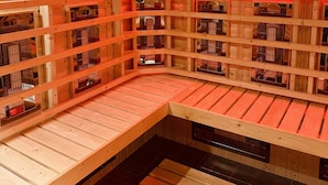 A sauna with wooden walls and benches, featuring multiple benches and a central open space. - The Q Hotel (Shanklin)