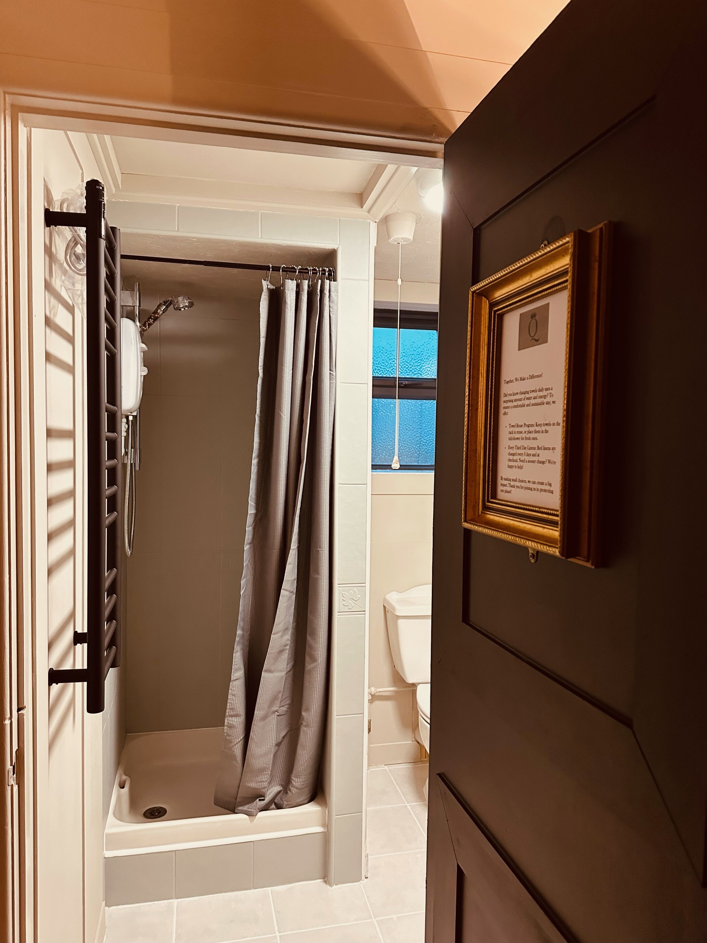 A bathroom with a shower, toilet, and a framed quote on the wall.
