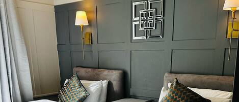 A hotel room with two beds, a bedside table, a lamp, and a wall decoration.