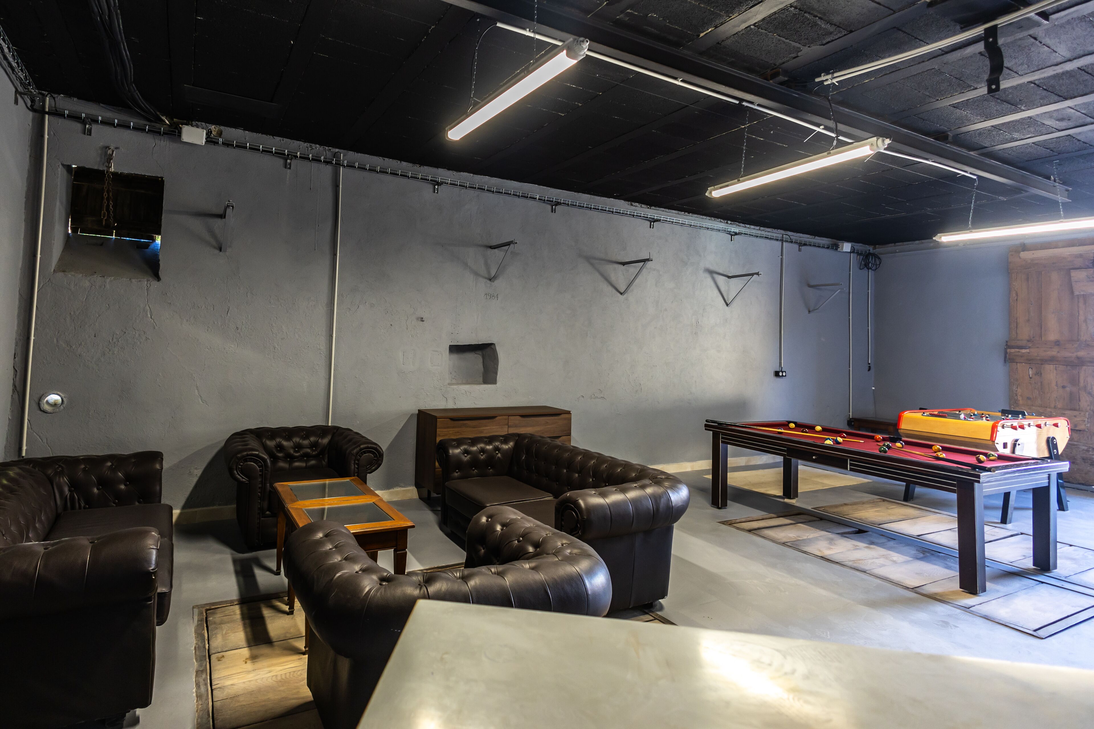 Una habitación con mesa de billar, sofás de cuero y un mueble de madera.