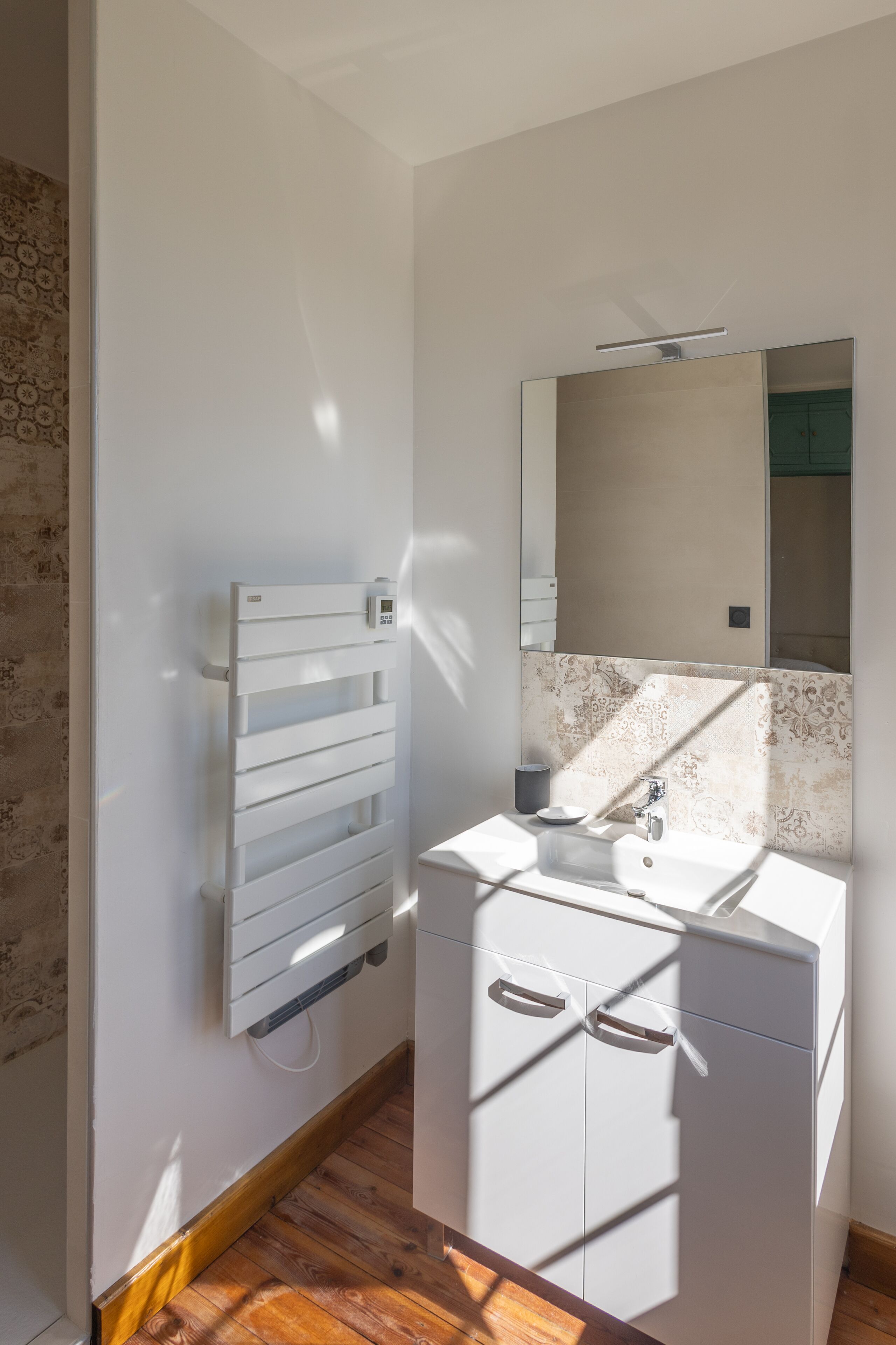 Un baño moderno con tocador blanco, toallero y espejo.