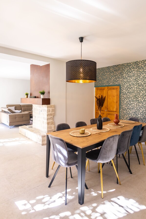 A modern dining area with a wooden table, grey upholstered chairs, and a black pendant light.