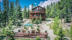 Escape to a serene forest retreat with a lodge offering a multi-level structure and patio with outdoor seating.