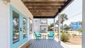 A covered porch with a wooden ceiling, turquoise doors, and matching chairs. - Home & Cabana House | Pool | Steps to the Beach! (Destin)