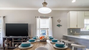 A dining area with a wooden table, blue and white plates, and a bowl of fruit. - Home & Cabana House | Pool | Steps to the Beach! (Destin)