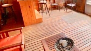 Un patio couvert doté d’un plancher en bois, d’un comptoir-bar et de différents espaces pour s’asseoir.