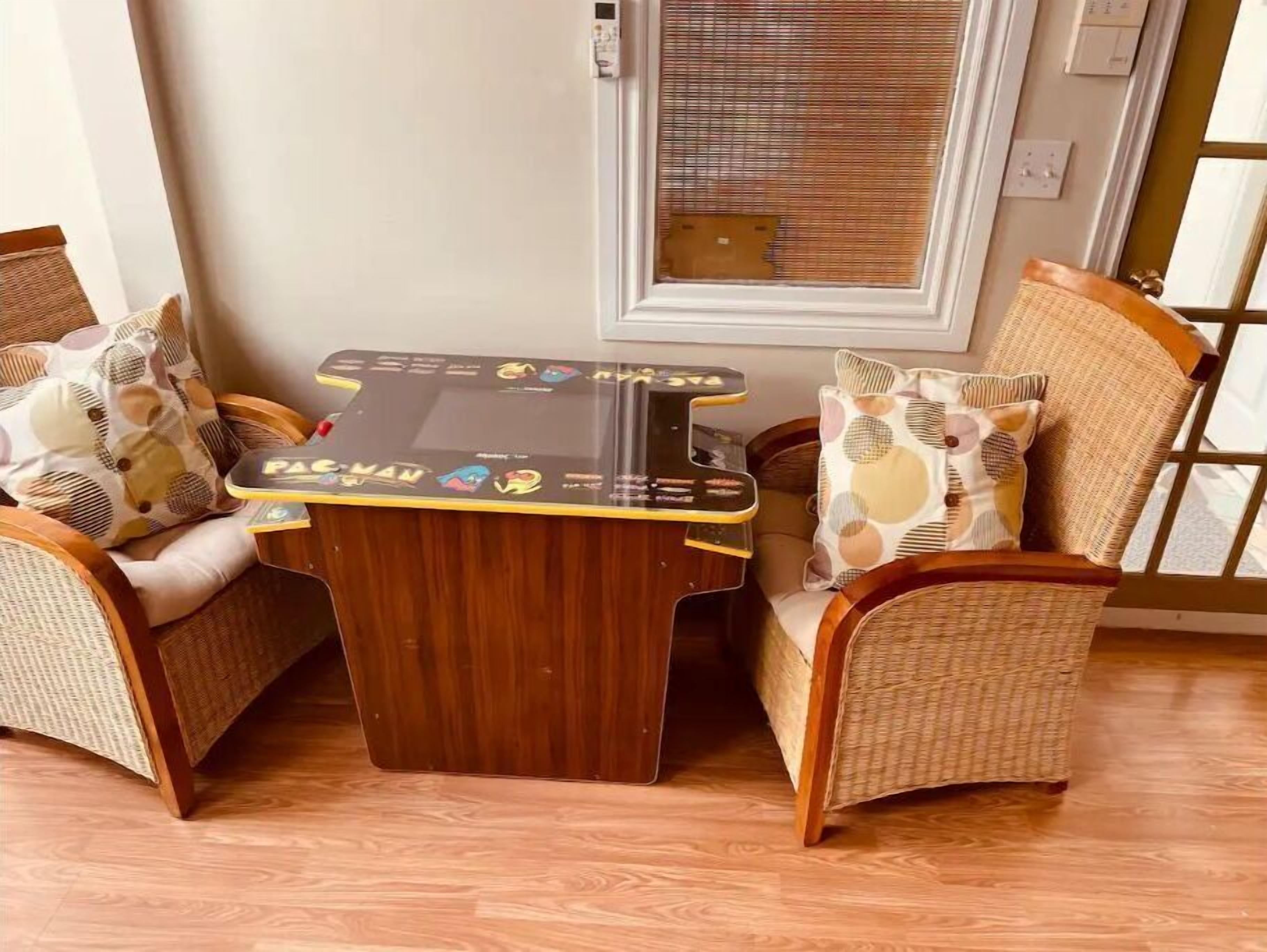 Un rincón con asientos de mimbre y una pequeña mesa de madera con un juego.