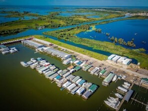 An aerial view of a marina with multiple docked boats and a large building complex. - HOUSEBOAT 2br/1ba RENOVATED, MAIN DOCK, Sleeps 7-8/Venice Marina (Venice)