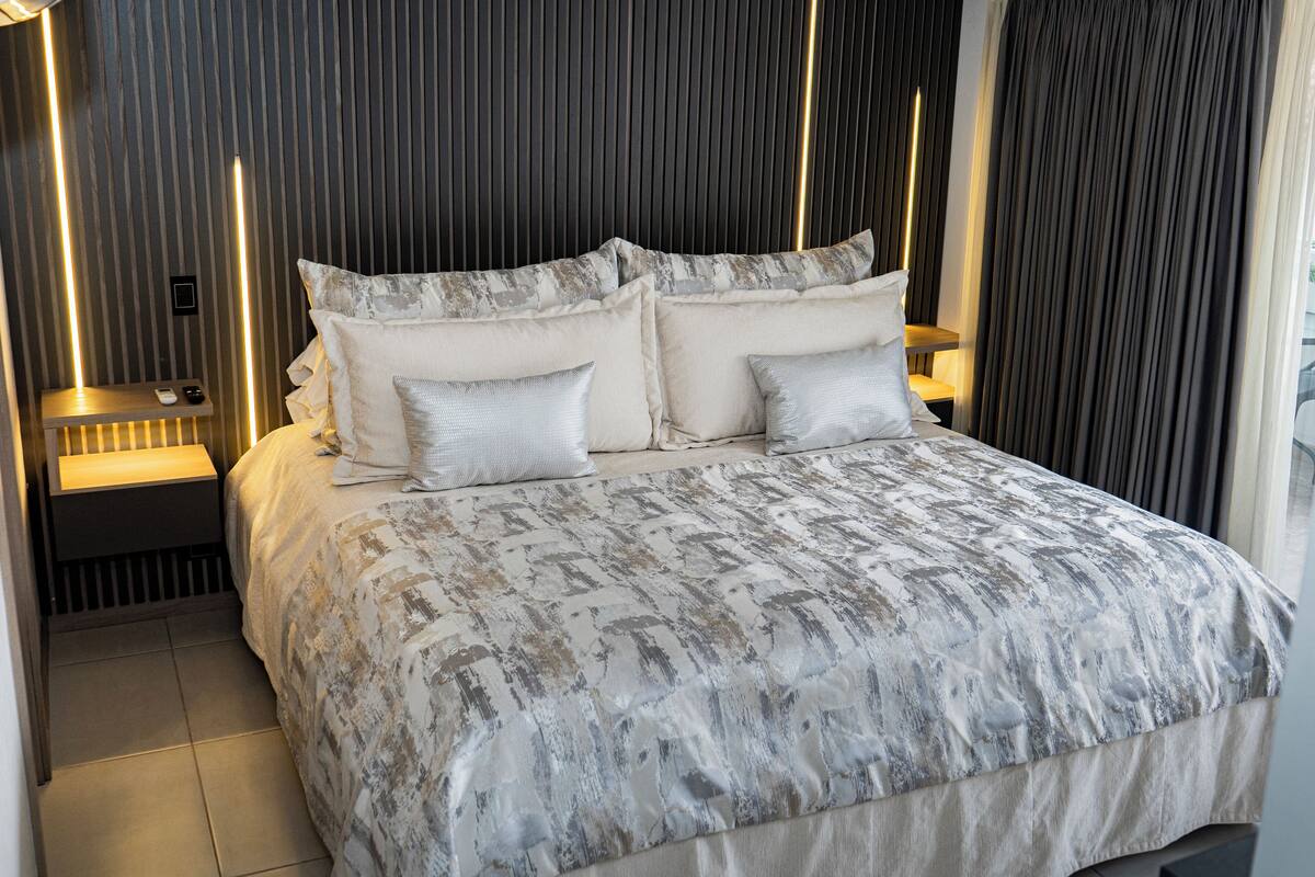 Een moderne slaapkamer met een groot bed, twee nachtkastjes en een wandlamp.