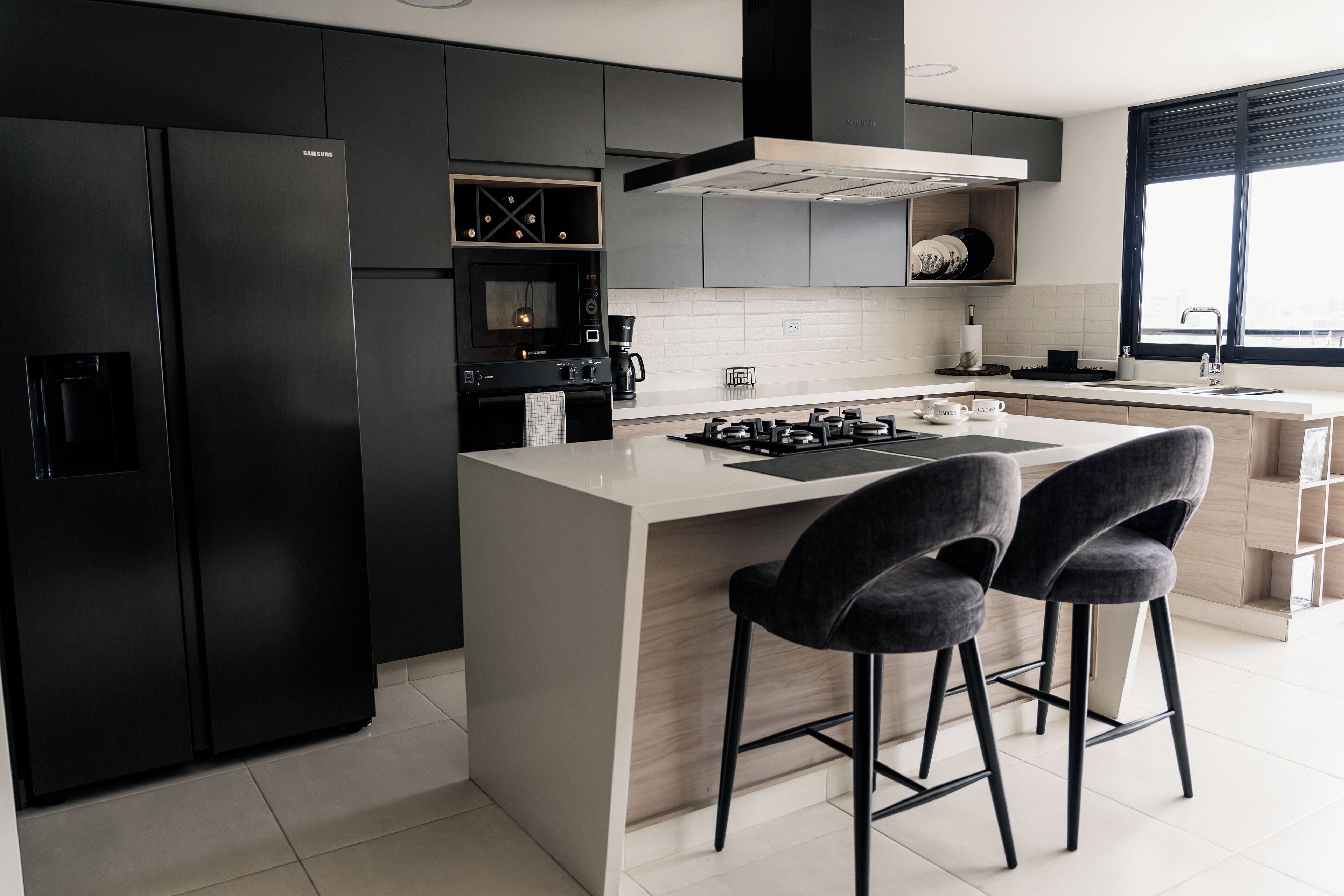 A modern kitchen with a central island, black appliances, and bar stools.