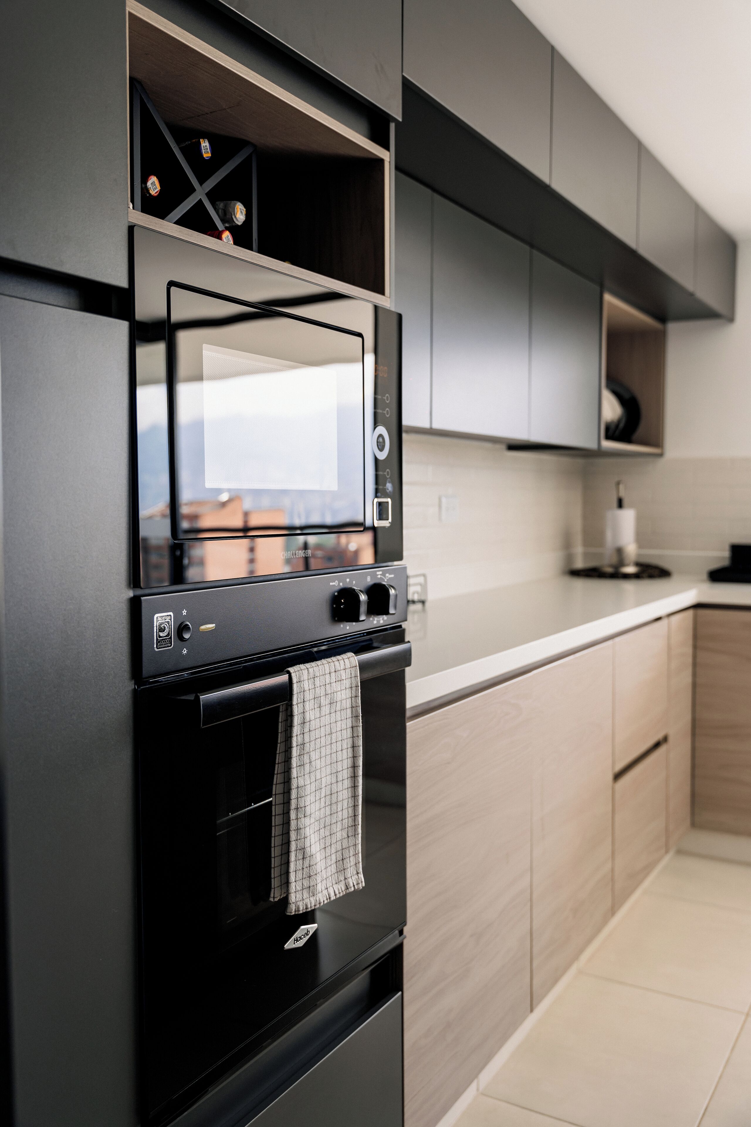 Una cocina moderna con horno integrado, microondas y una pequeña ventana sobre el horno.
