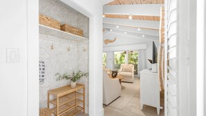 Una sala de estar moderna con un sofá, una mesa de centro y un televisor. Hay cestas de mimbre en estantes y una planta sobre una mesa de madera.