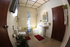 A bathroom with a toilet, sink, shower, and a mirror.