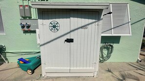 A utility shed with a circular logo, a laundry sign, and a green toy car nearby.