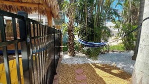 A fenced outdoor area with a hammock, palm trees, and a gravel path.