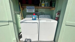A laundry room with two washing machines, a notice board, and a fire extinguisher.
