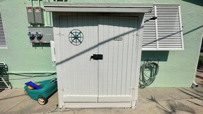 A utility shed with a circular logo, a laundry sign, and a green toy car outside. - Turtle Nest 5 - Quick Walk to Beach (Fort Myers Beach)