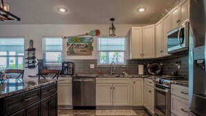 A kitchen with white cabinets, stainless steel appliances, a dishwasher, and a granite countertop.