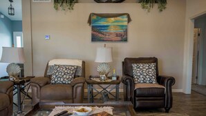 A living room with two leather sofas, a coffee table, and a painting of a beach scene on the wall.