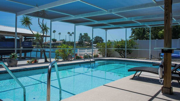 A pool area with a covered section, lounge chairs, and a lifeguard stand.