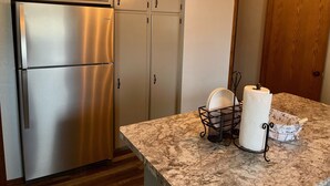 Una cocina con un refrigerador de acero inoxidable, armarios de madera y una encimera de mármol.