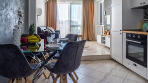 Eine moderne Küche mit Essbereich, inklusive Glastisch, dunklen Stühlen und einem eingebauten Backofen.
